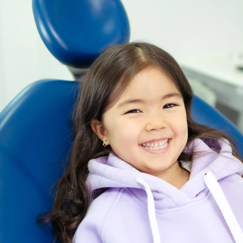 A child smiling comfortably in a dental chair